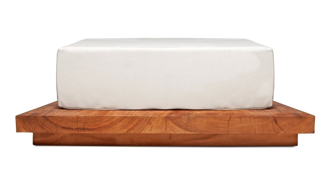 A white cushion on a wooden daybed suar placed on a sleek, cylindrical design daybed